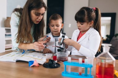 Çocuklar anneleriyle evde kimyasal deneyler yapıyorlar.