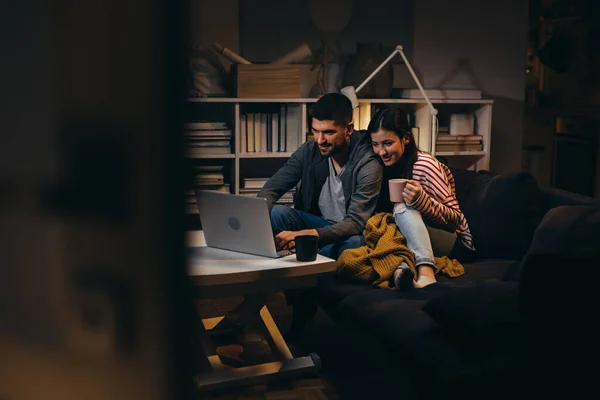 young couple using laptop computer at home. evening scene