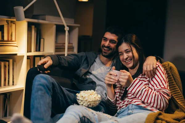 Evde birlikte televizyon izleyen genç bir çift.