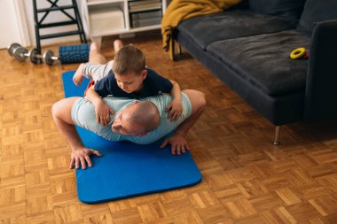 Baba ve oğul evde egzersiz yapıyor.