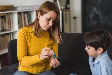 Anne çocuğuna astım pompasını nasıl kullanacağını anlatıyor.