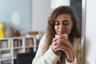 Güzel bir kadın sabah kahvesini içiyor. Kahveyi koklarken gözlerini kapat.