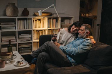 Orta yaşlı çift evde şarap içiyor.