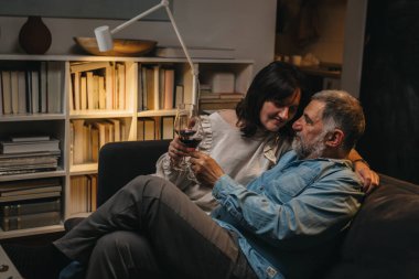 Orta yaşlı çift evde şarap içiyor..