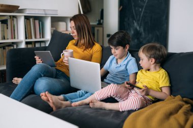 Evde dizüstü bilgisayar ve dijital tablet kullanan asosyal aile