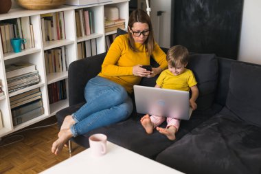 Anne ve oğlu evde dizüstü bilgisayar kullanıyorlar.