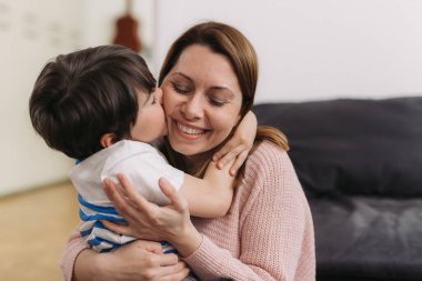 Anne oğluyla sarılıp öpüşüyor.