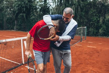 Baba ve oğul dışarıda tenis oynuyorlar.