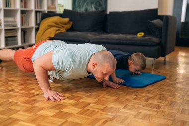 Baba ve oğul evde egzersiz yapıyor.