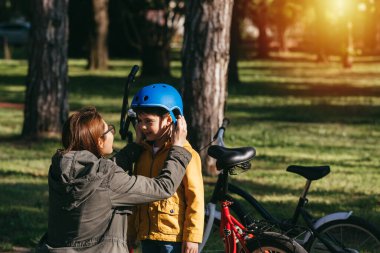 Anne ve çocuk halk parkında bisiklet sürmeye hazırlanıyor.