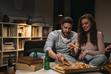 Arkadaşlar evde birlikte ders çalışırken pizza yiyorlar.