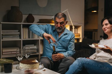 Orta yaşlı çift evde doğum gününü kutluyor.