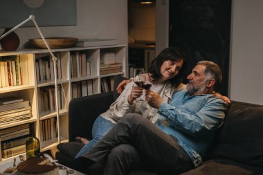 Orta yaşlı çift evde pasta ve şarapla kutlama yapıyor.