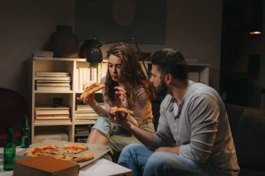 Çiftler evde pizza yerken eğleniyorlar.