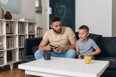 Baba ve oğul evde bilgisayar oyunu oynuyorlar.