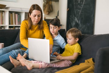 Anne ve oğulları dizüstü bilgisayar kullanıyor.