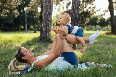 Anne oğluyla dışarıda fiziksel egzersiz yapıyor.