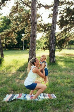 Anne oğluyla dışarıda fiziksel egzersiz yapıyor.