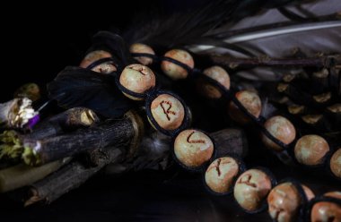 Runik alfabeden bir kolye iplikle dönen dallardan oluşan ritüel bir koleksiyonda yatıyor.