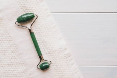 Yeşil kuvarstan yapılmış yeşil taş silindir, gua sha yüz masajı için doğal bir alet. Üst görünüm beyaz arkaplan, kopyala boşluk, kapat. Güzellik ve vücut bakımı.