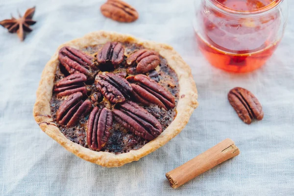 Delicious freshly baked homemade mini pecan pie on white tablecloth.