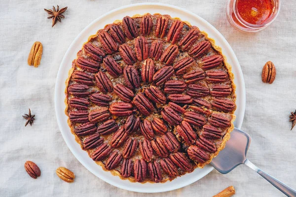 Delicious freshly baked homemade pecan pie on white tablecloth.