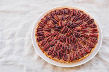 Beyaz masa örtüsünde taze pişmiş nefis ev yapımı cevizli turta. Üst manzara, düz yatış. Şükran Günü ve Noel için popüler bayram yemeği.