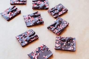 Kırmızı meyveli siyah çikolata parçaları kağıt kaplama arka planda, yakın plan. Boşluğu kopyala.