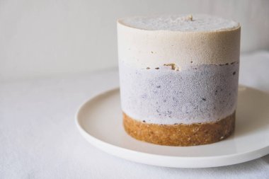 Çiğ glütensiz fırınlanmamış tatlı. Beyaz arka planda vegan vanilyalı yaban mersinli cheesecake. Tatlı sağlıklı yemek..