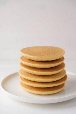 Taze pişmiş, yumuşak, lezzetli glütensiz krepler, beyaz tabağa istiflenmiş, yakın plan. Mesaj için yer var. Sağlıklı tatlı yiyecekler.