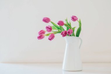 Mor lalelerden oluşan güzel bir buket beyaz vazoda çiçek açıyor..