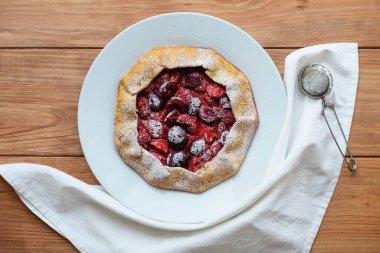 Ahşap arka planda taze pişmiş vejetaryen çilek ve kiraz galeti, üst manzara. Tatlı yemek, yaz tatlısı..