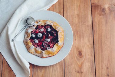 Ahşap bir arka planda taze pişmiş vegan çilek ve kiraz galeti. Mesaj için yer. Tatlı yemek, yaz tatlısı..