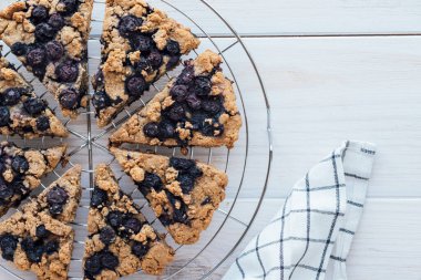 Beyaz ahşap zemin üzerinde taze pişmiş yaban mersinli çörekler. Yüksek açı. Vejetaryen ve bitki bazlı hamur işi. Tatlı yemek..