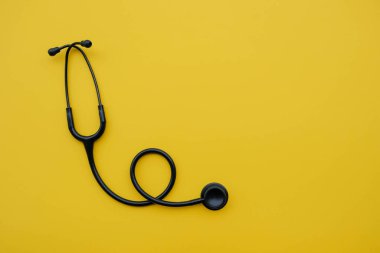 Sarı arka planda siyah tıbbi steteskop..