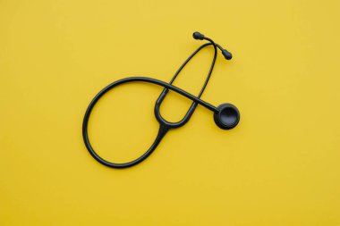 Sarı arka planda siyah tıbbi steteskop..