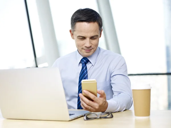 Mensen uit het bedrijfsleven werkzaam in kantoor met mobiele telefoon en laptop — Stockfoto