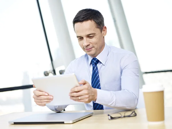 Бизнесмен, использующий планшет в офисе — стоковое фото