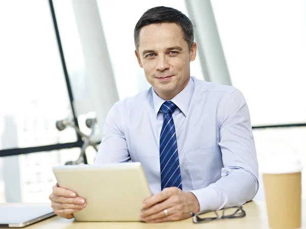 Бизнесмен, сидящий в офисе с планшетом — стоковое фото