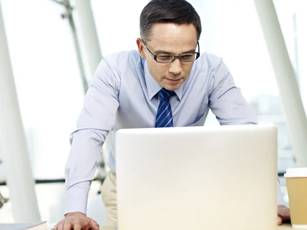 Konzernchef schaut im Büro auf Laptop — Stockfoto