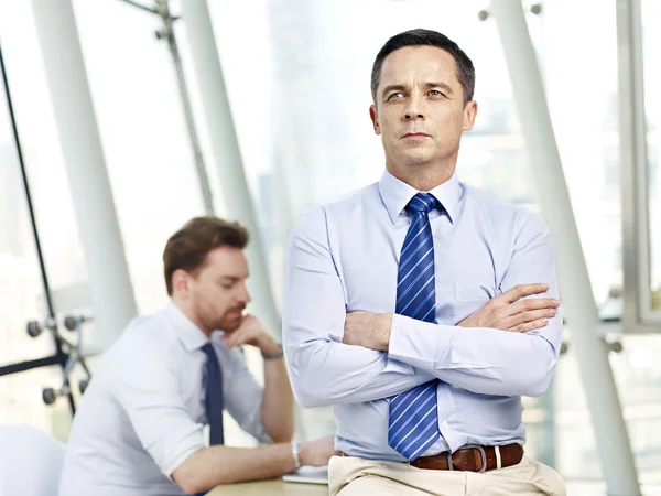 Överväger business person sitter på skrivbord i office — Stockfoto