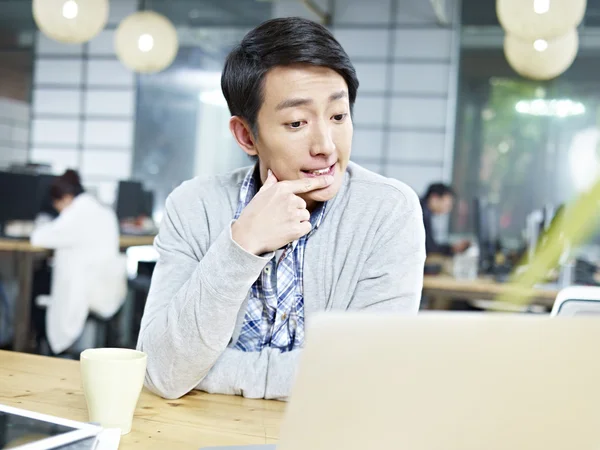 Молода азіатська бізнесмен думає важко в офісі — стокове фото