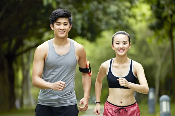 Unga asiatiska par kör jogging i en park — Stockfoto