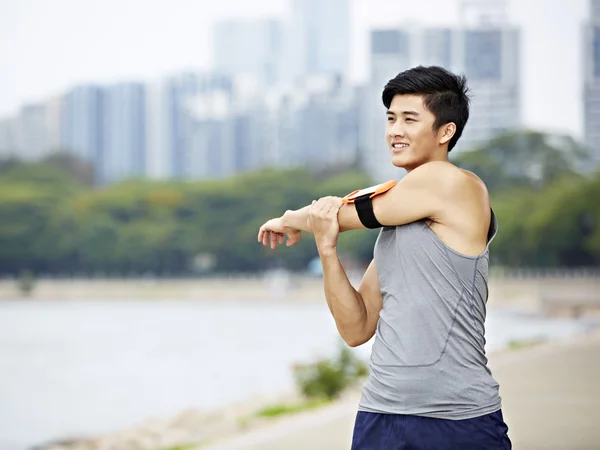Joven asiático jogger estiramiento brazos antes de correr —  Fotos de Stock