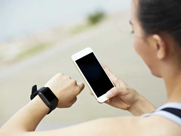 Mujer con teléfono celular y rastreador de fitness — Foto de Stock