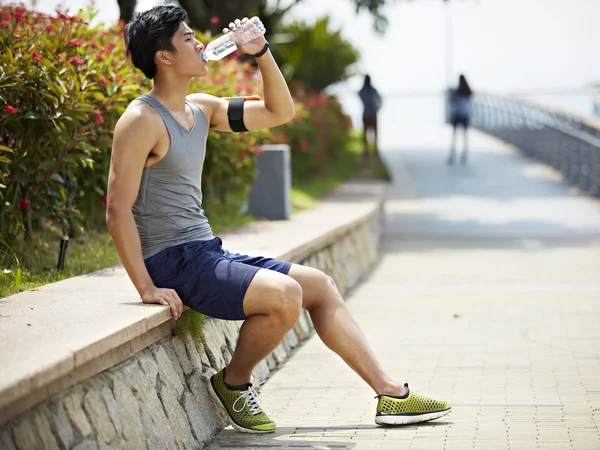 Joven asiático jogger descanso y beber agua —  Fotos de Stock