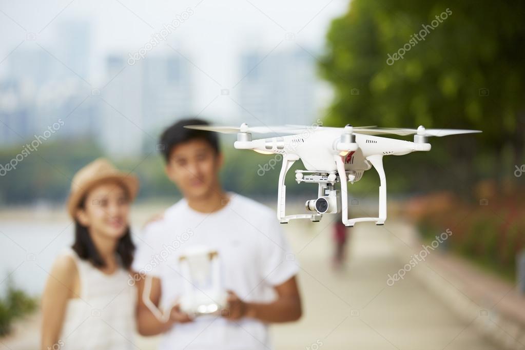 young asian couple operating a drone