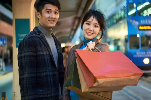 Happy Loving Young Asian Couple Standing Bus Station Shopping Bags — Stock Photo, Image