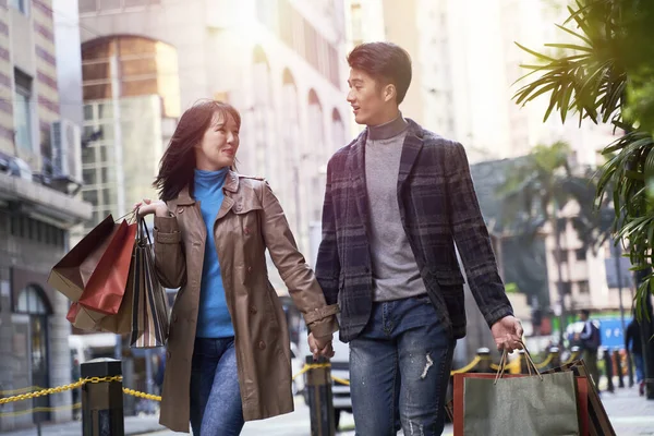 ショッピングバッグを手に街を歩く若いアジアのカップルを愛し — ストック写真