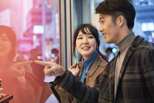 loving young asian couple looking at shop window and talking